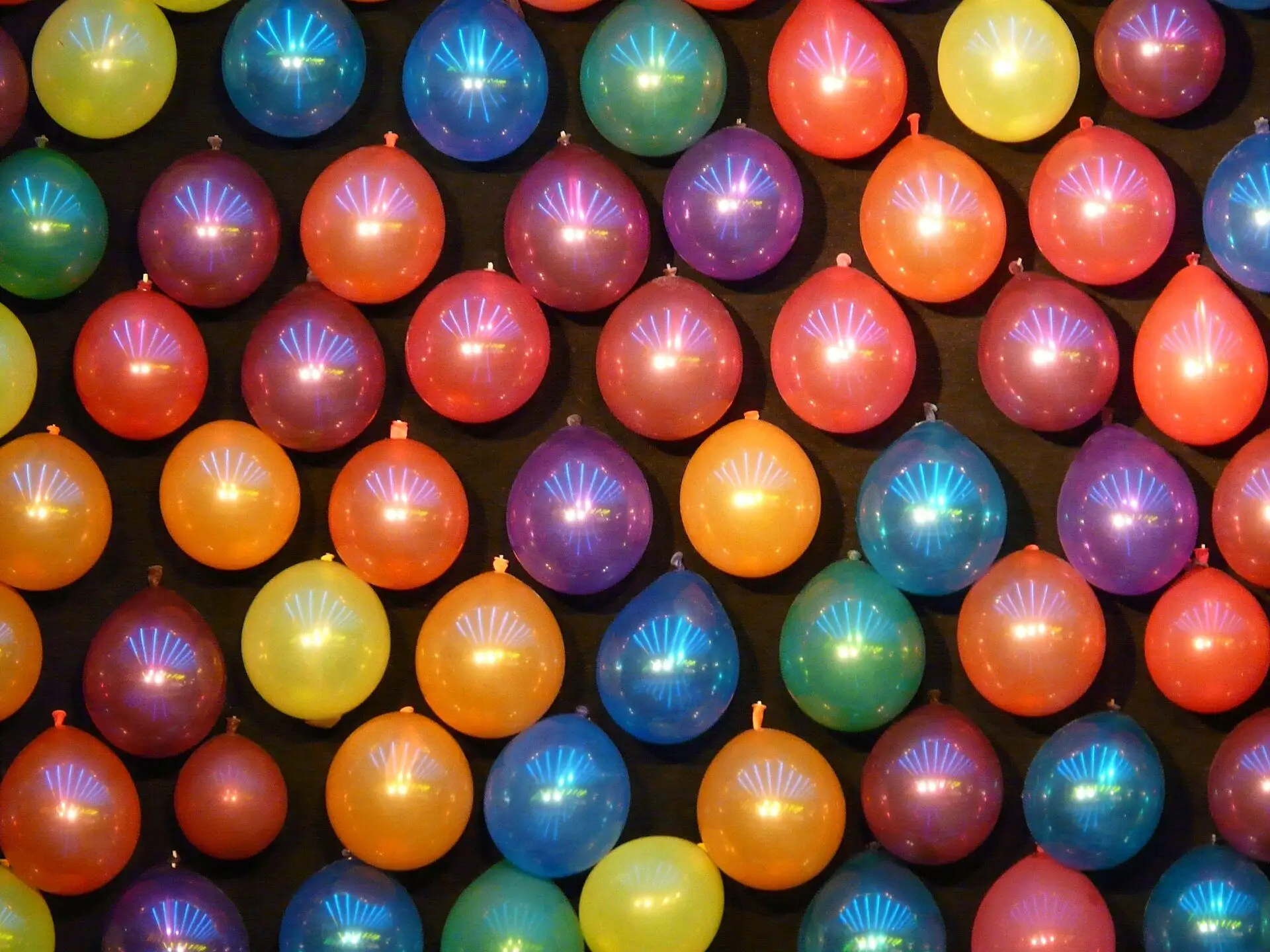 Rows of brightly coloured balloons on a wall