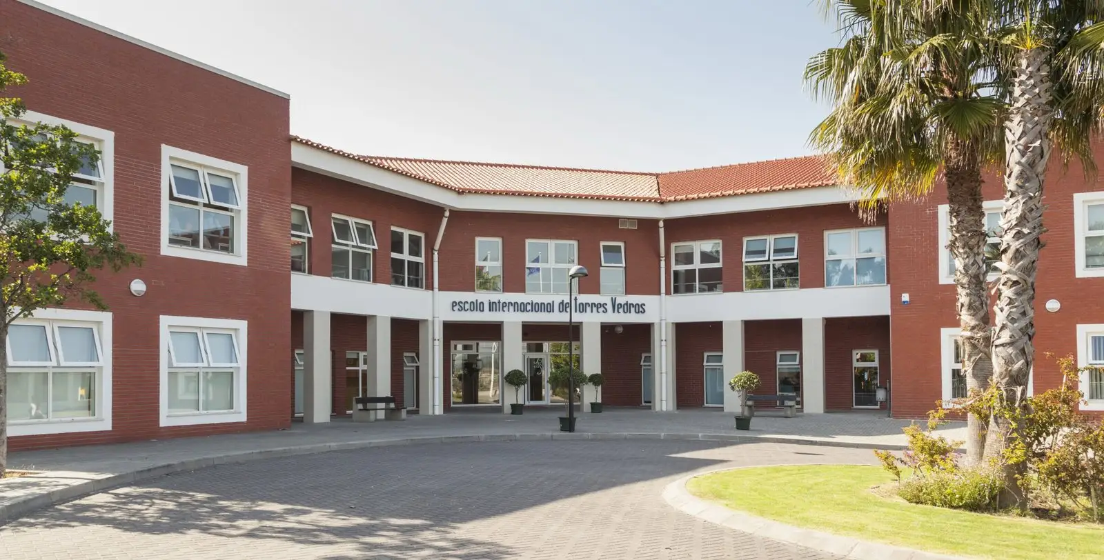 Red-brick main building and entrance courtyard of Escola Internacional de Torres Vedras