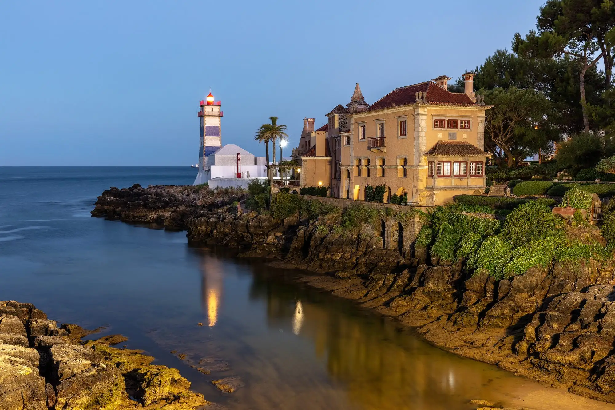 The Santa Marta lighthouse and a seafront villa in Cascais at dusk