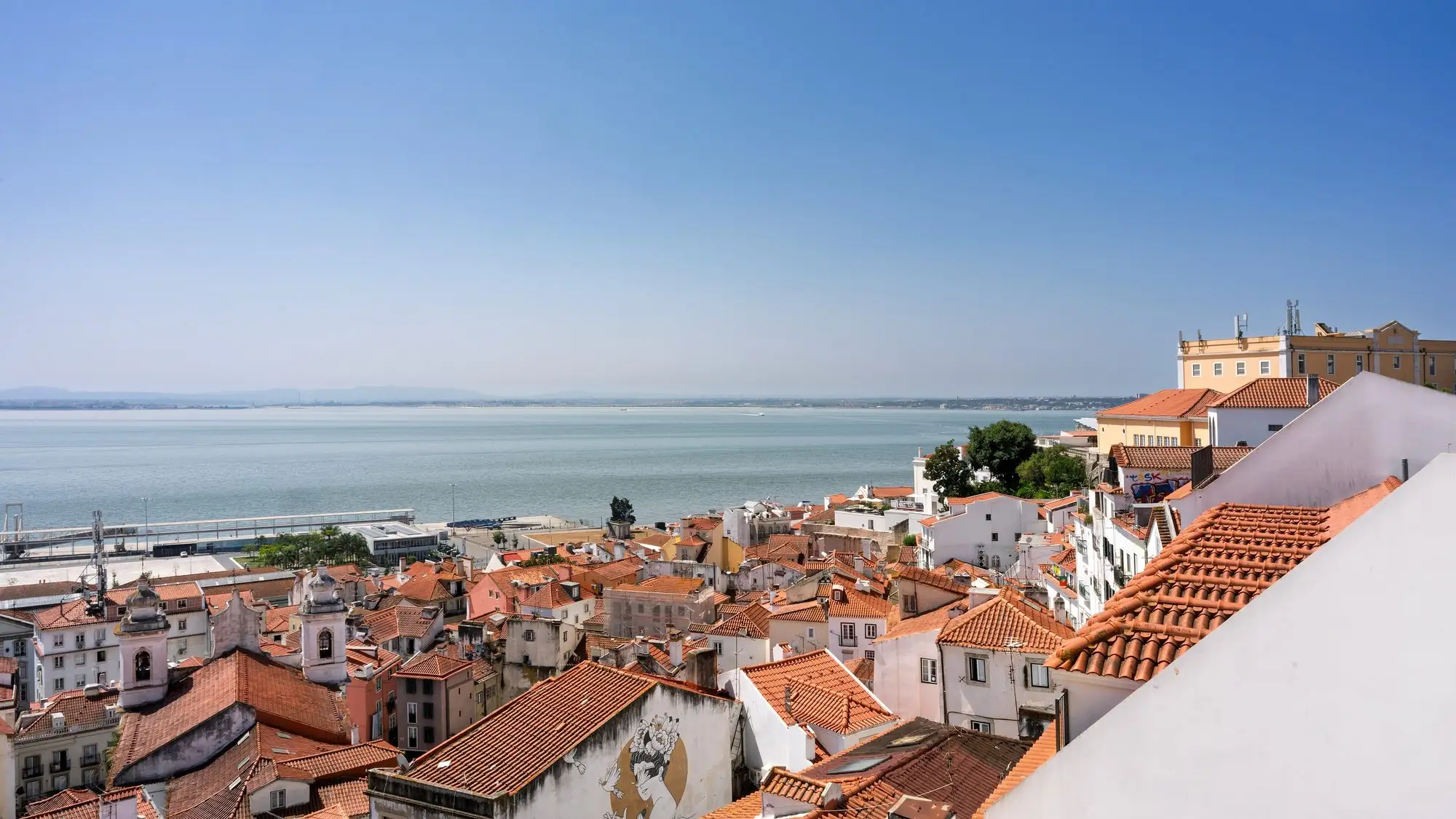 Terracotta rooftops of the Alfama district running down to the Tagus river in Lisbon